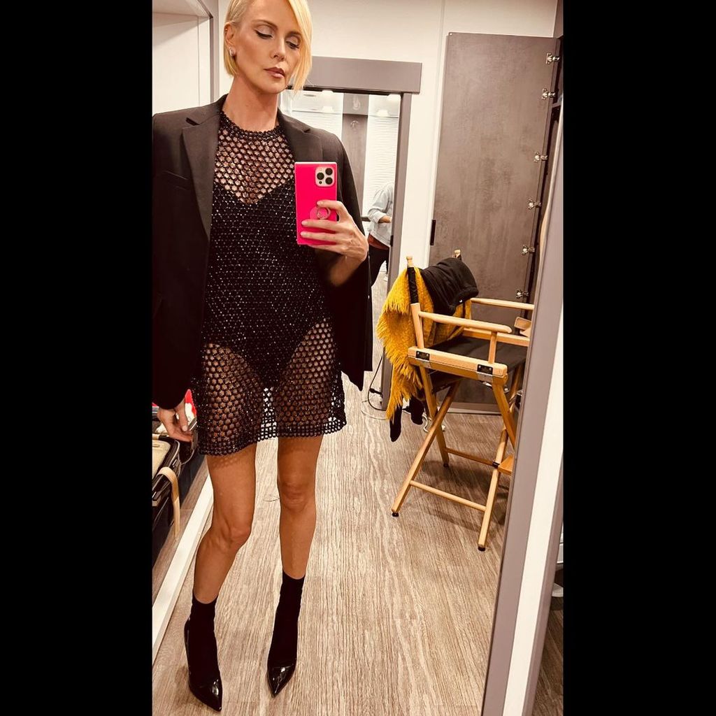 Charlize Theron poses for selfies in a swimsuit under a mesh dress posted on Instagram