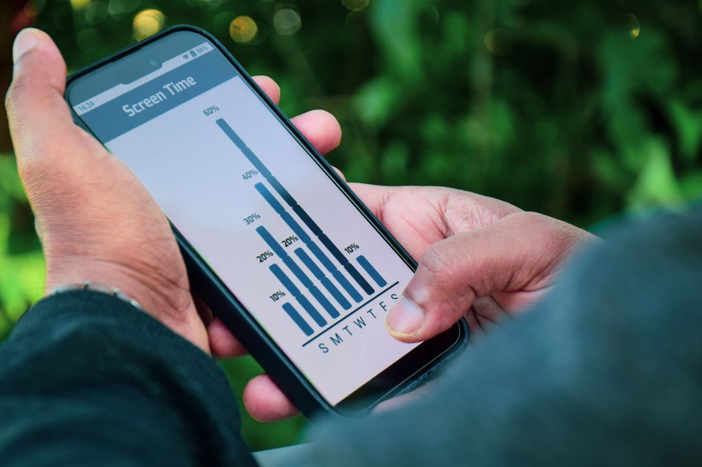 businessman checking the weekly screen time graph on his mobile phone