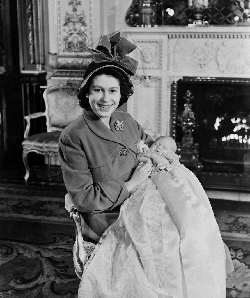 queen cradling baby in christening gown