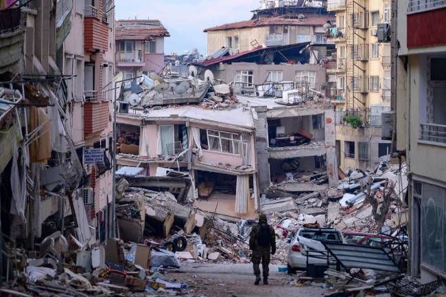 A Turkish soldier walks among destroyed buildings in Hatay, Turkey