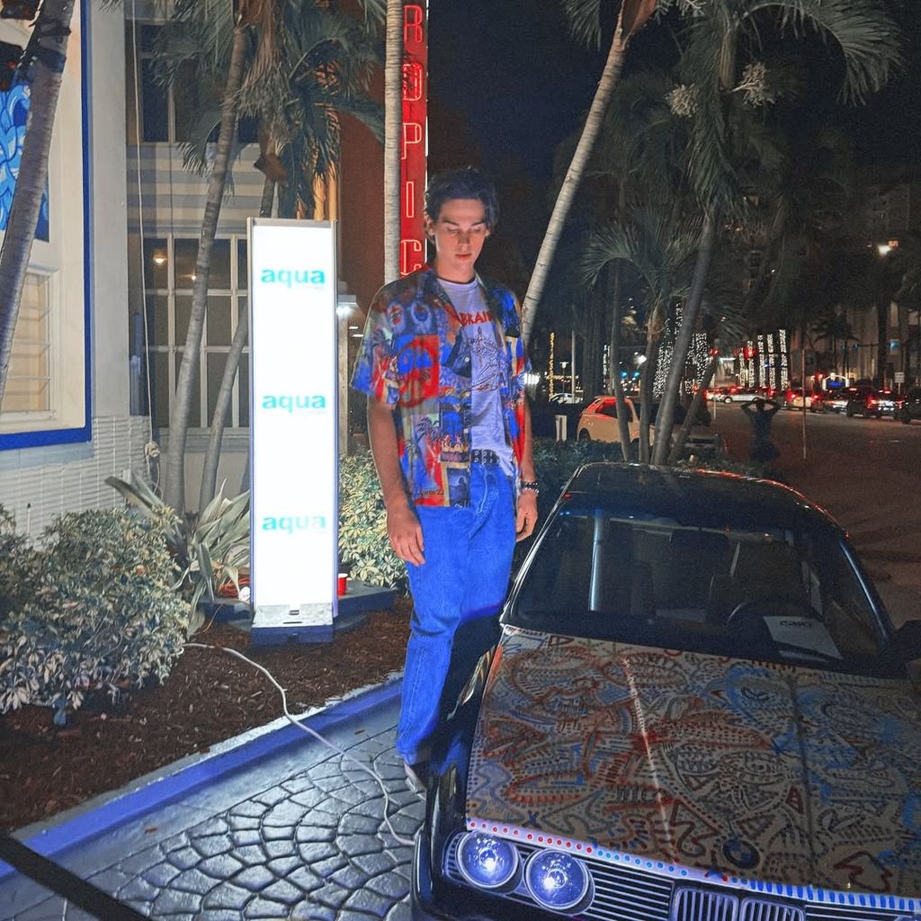 Paris Brosnan poses next to his BMW E30 after his live painting event at Art Basel in Miami, shared on Instagram