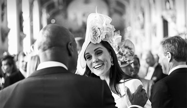 Kate Middleton wearing a hat and smiling with guest at Harry and Meghan's wedding
