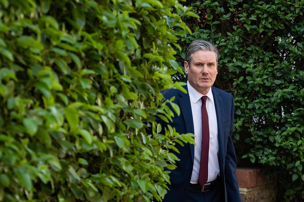 Keir Starmer in a suit next to a hedge