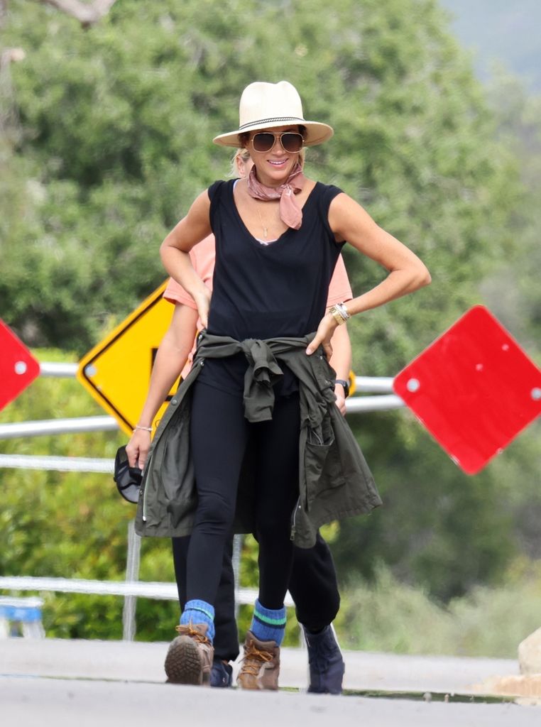 meghan markle in sporty black outfit and hat hiking with friends