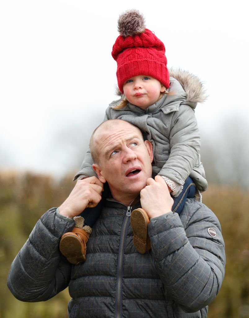 Mia Tindall wearing a red hat and sitting on Mike Tindall's shoulders
