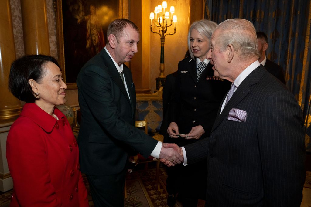 King Charles shaking hands with a man as two women look on