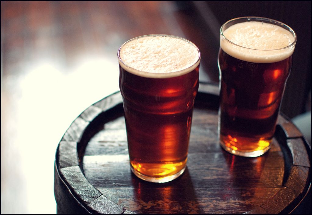Two pints of beer on wooden barrel in London pub. Our top choice for a pint in London is the city's oldest pub, The Seven Stars.