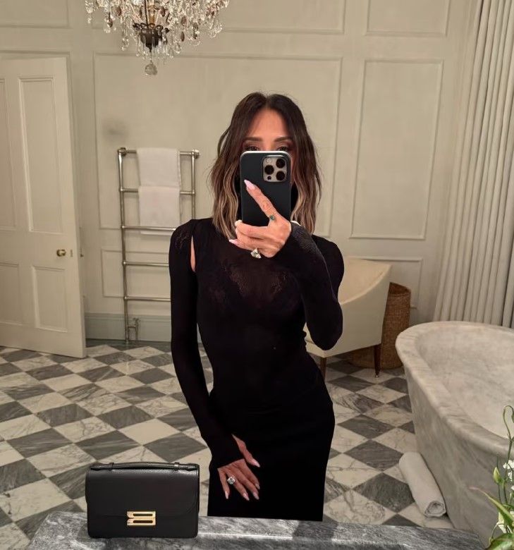 Victoria Beckham wearing black, taking a selfie in a bathroom