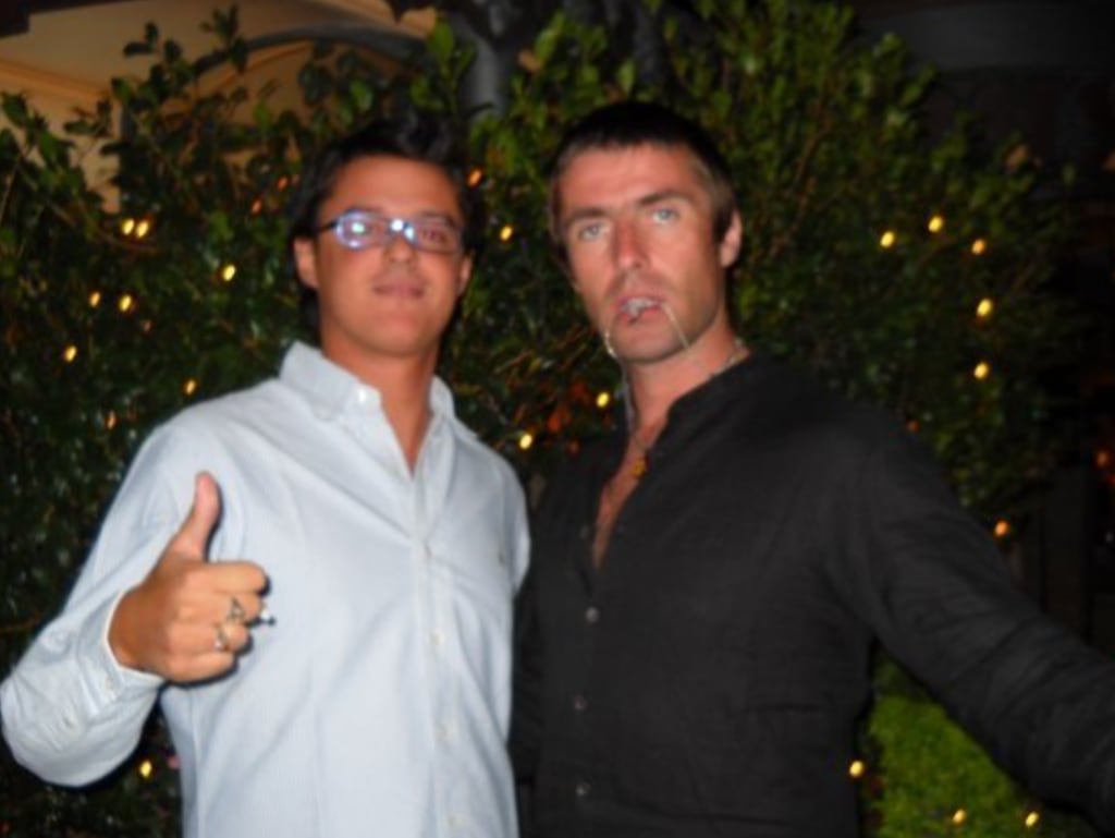 Liam Gallagher posing with fan outside a bar
