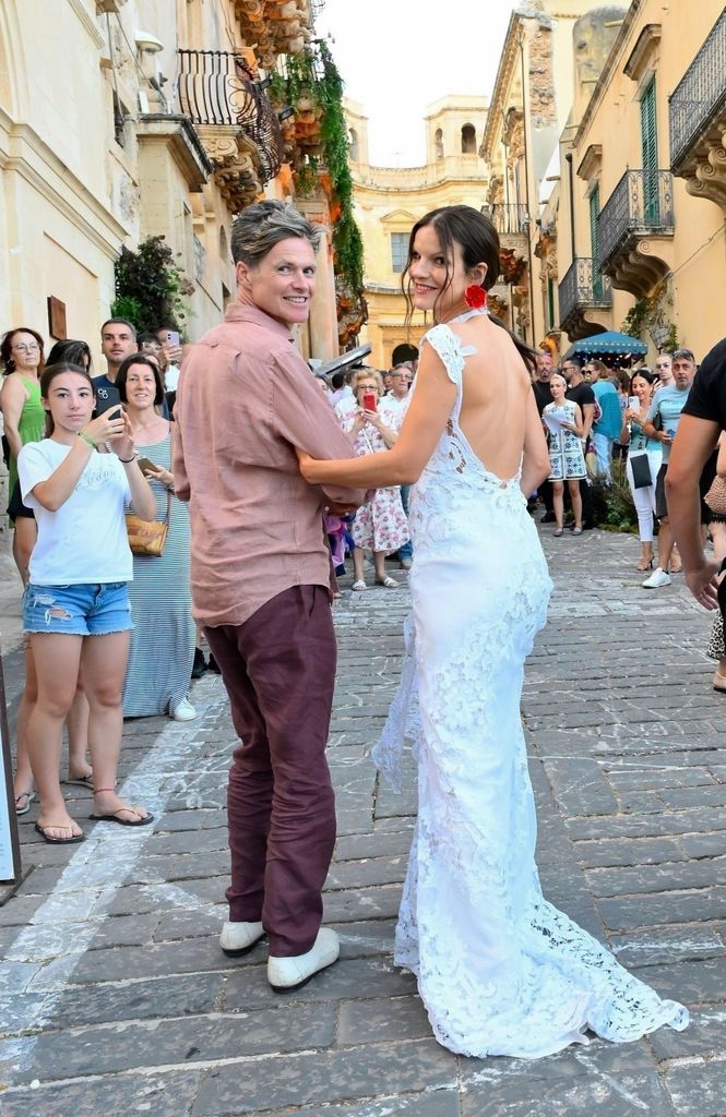 Kate in a white backless gown beside husband on street