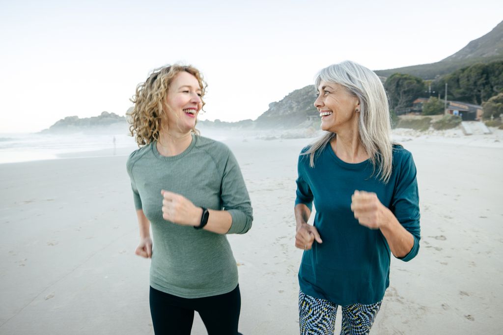 Two middle-aged sporty women exercising  along the beach in athletic wear.