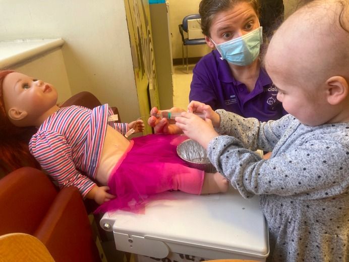 child pretending to inject doll