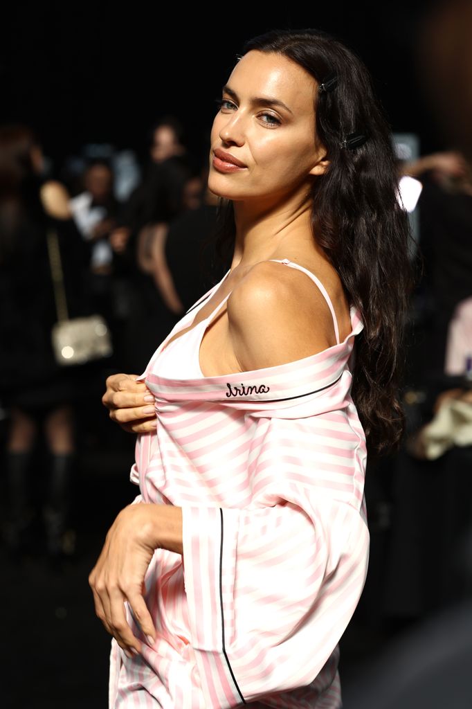 Irina Shayk stole the backstage spotlight, effortlessly posing in her signature pink robe. With her name stitched on the fabric and a smoldering expression, she gave off an aura of timeless elegance and confidence, perfectly embodying the Victoria’s Secret allure.