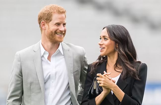 prince harry in grey suit smiling at wife meghan markle