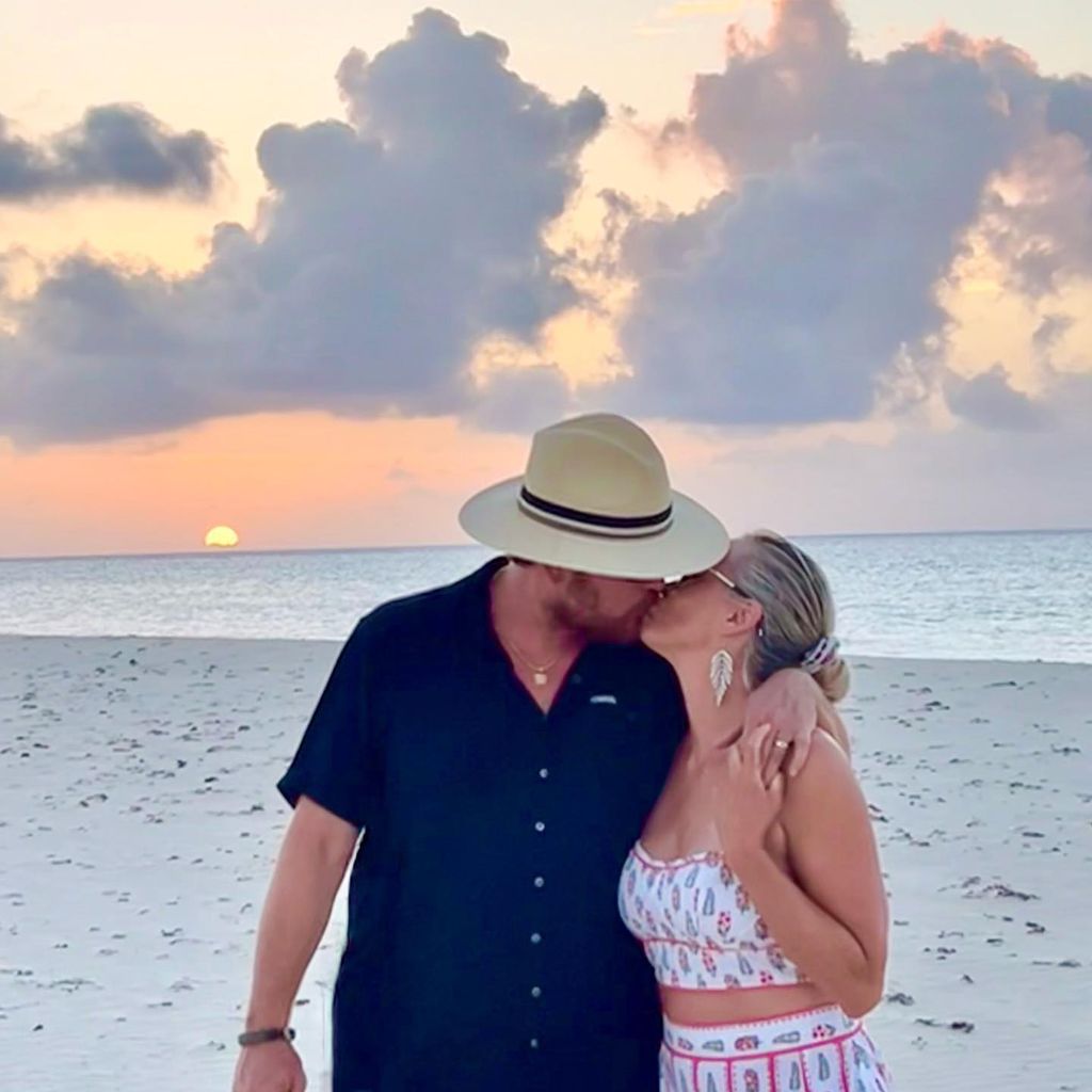Cole and Cynthia Hauser kiss on the beach at sunset 