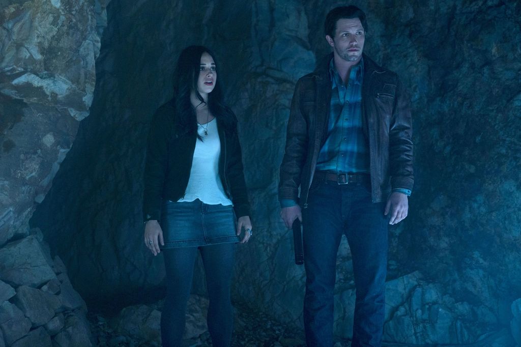 woman and man standing in dark cave