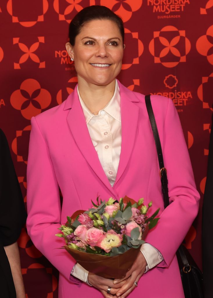 Crown Princess Victoria in a pink suit holding a bouquet of flowers