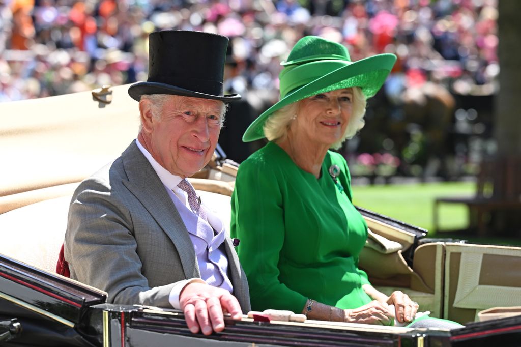 King Charles in grey suit and top hat and Queen Camilla in green dress and hat