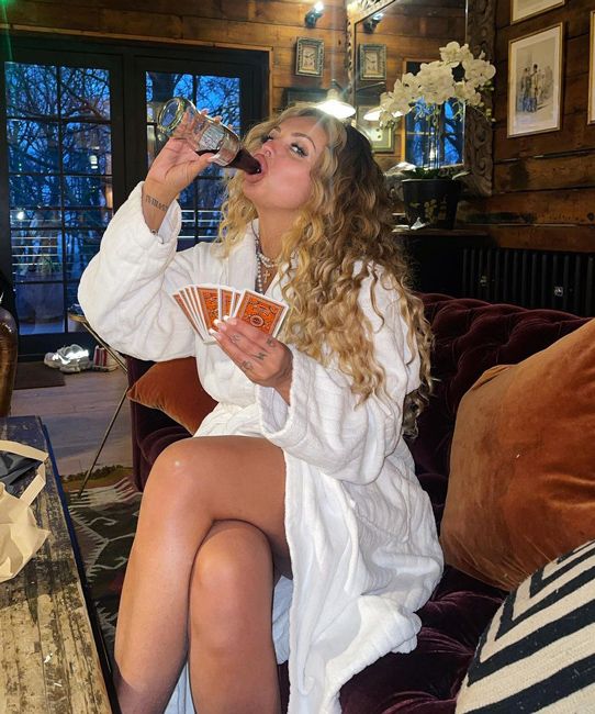 jesy wears a leg baring robe and holds playing cards