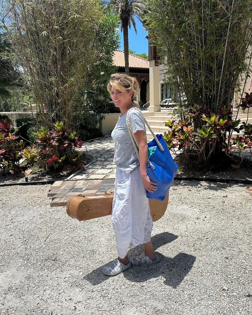 Shania Twain wearing a summer outfit and carrying a guitar