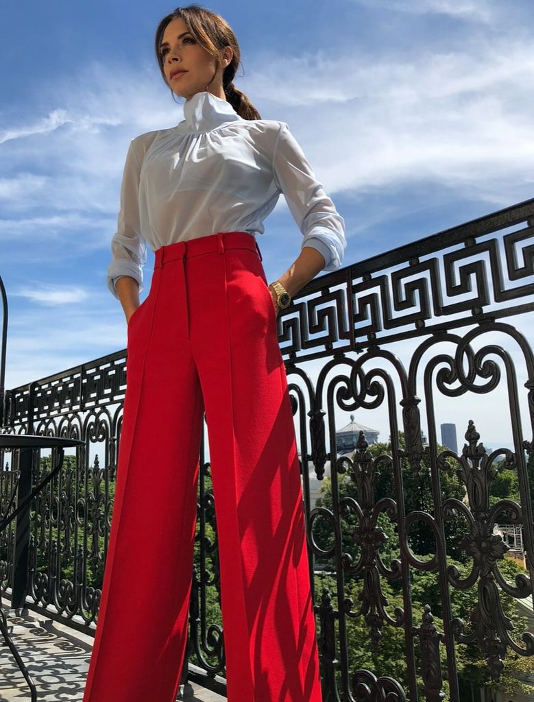 Victoria Beckham wearing a stylish outfit of a blue top and red trousers