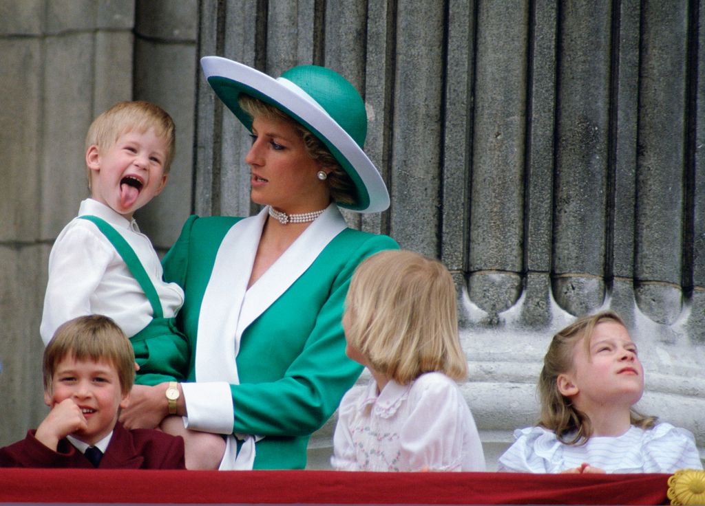 Princess Diana holding a young Prince Harry who is sticking out his tongue