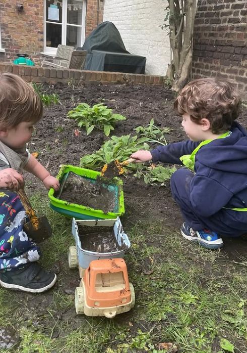 Two young children playing in a garden and getting muddy