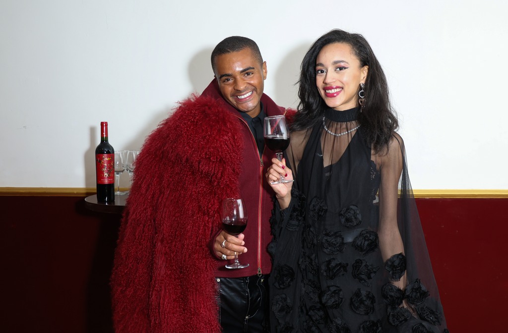 Layton Williams and Paris Smith smiling holding glasses of red wine