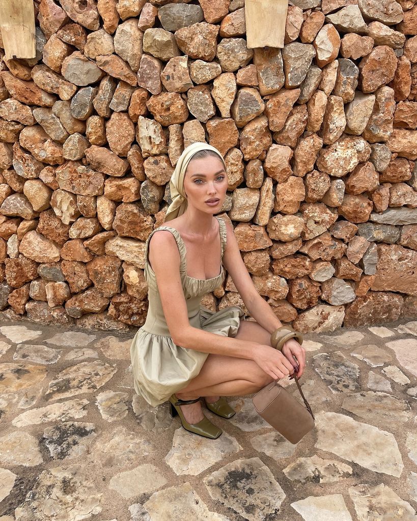 Elsa Hosk crouches in front of the camera wearing a taupe headscarf and matching mini dress, heeled mary jane shoes and handbag
