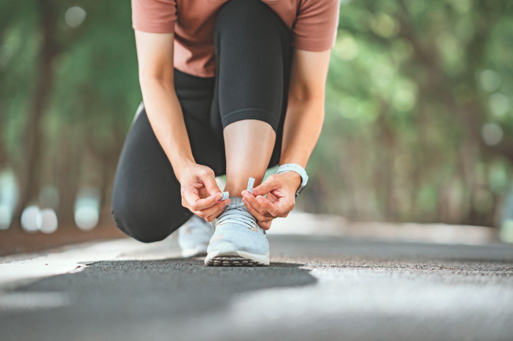 woman kneeling down to lace up her running trainers