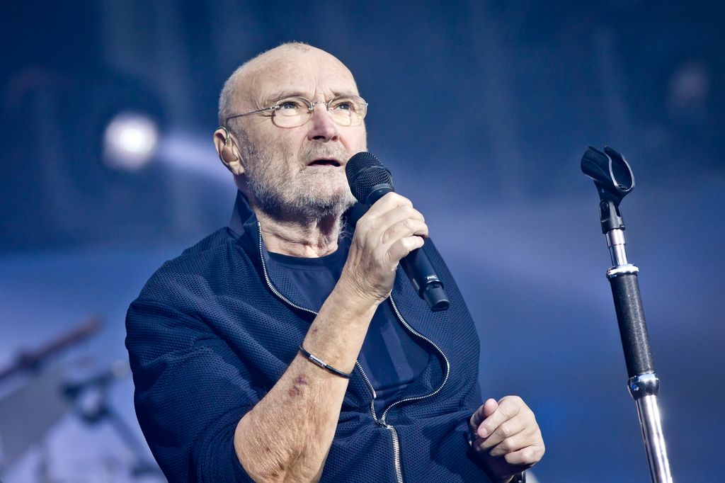 phil collins holding microphone on stage