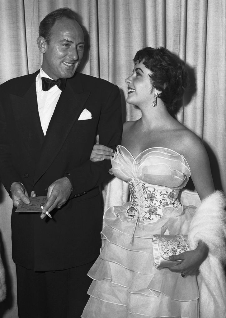 Elizabeth Taylor in a ruffled dress looking at her husband Michael Wilding