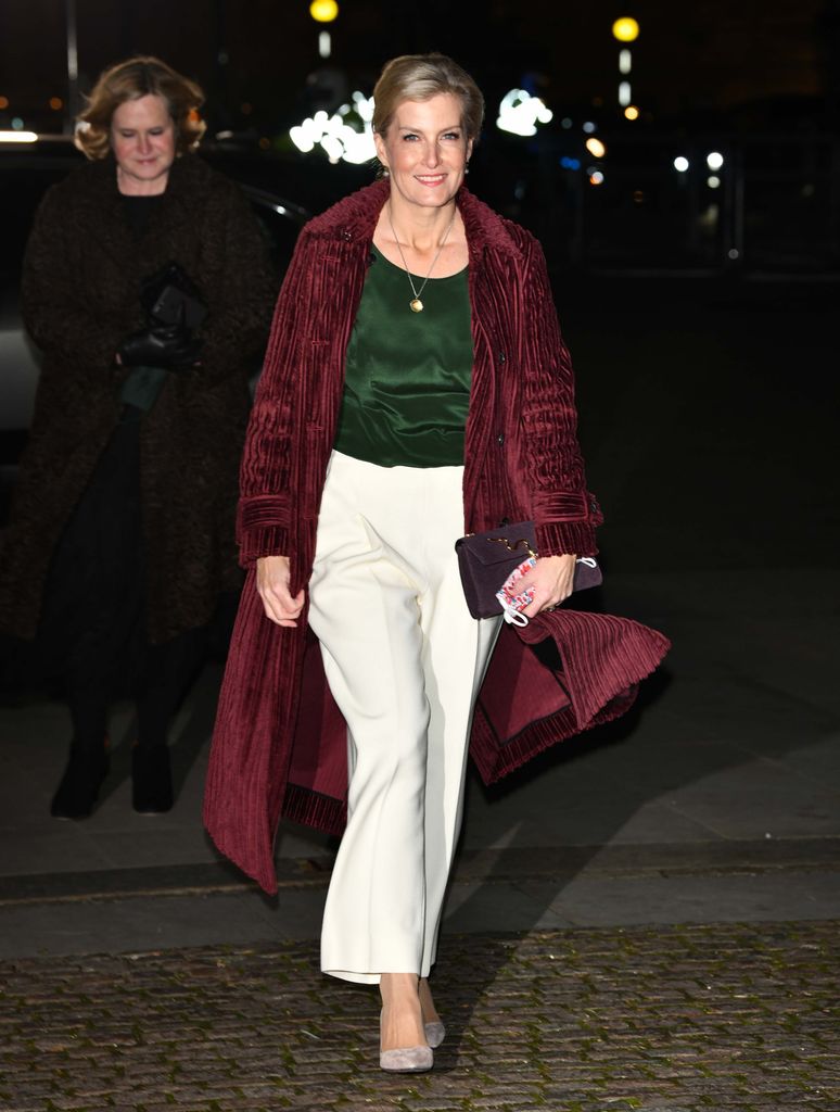Sophie at night in burgundy coat and white trousers