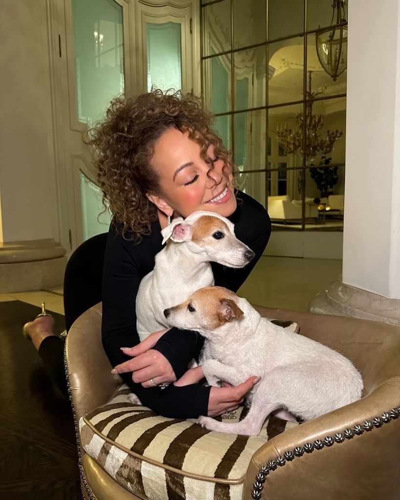 Mariah Carey in black dress cuddling two jack russell pet dogs 