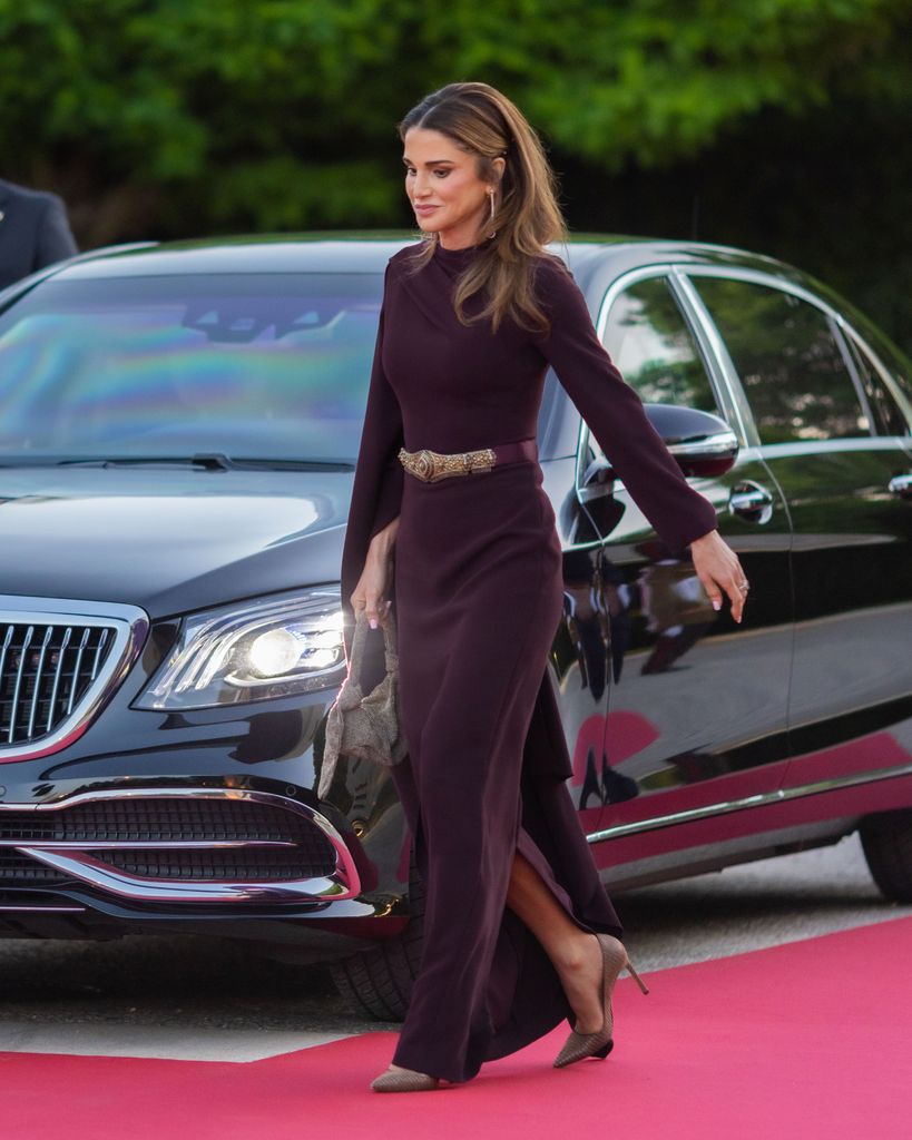 Queen Rania walking next to a car with curled hair