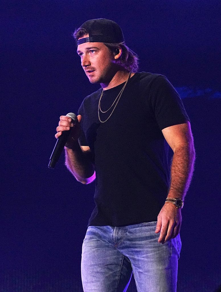 Morgan Wallen on stage with a microphone wearing a plain black tshirt