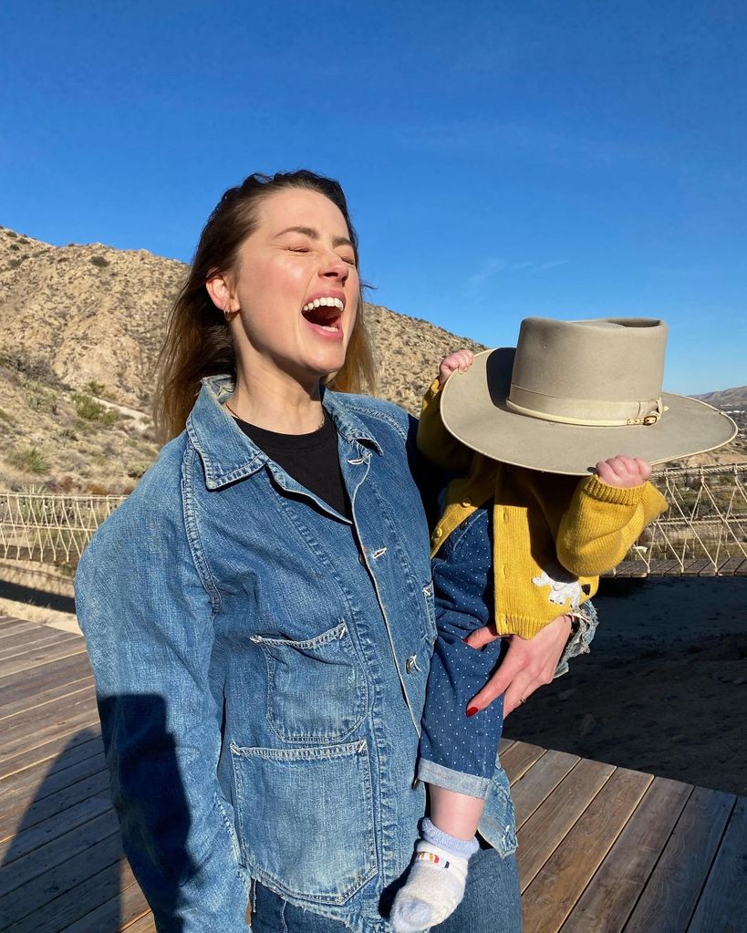 Amber Heard holding her daughter Oonagh Paige who is wearing her hat