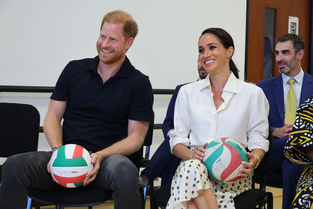 Prince Harry and Meghan sitting holding basketballs