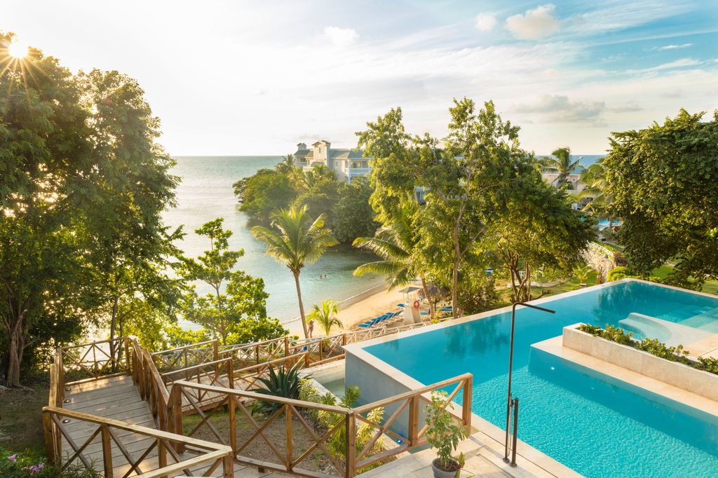 pool with staircase and trees surrounding with beach below