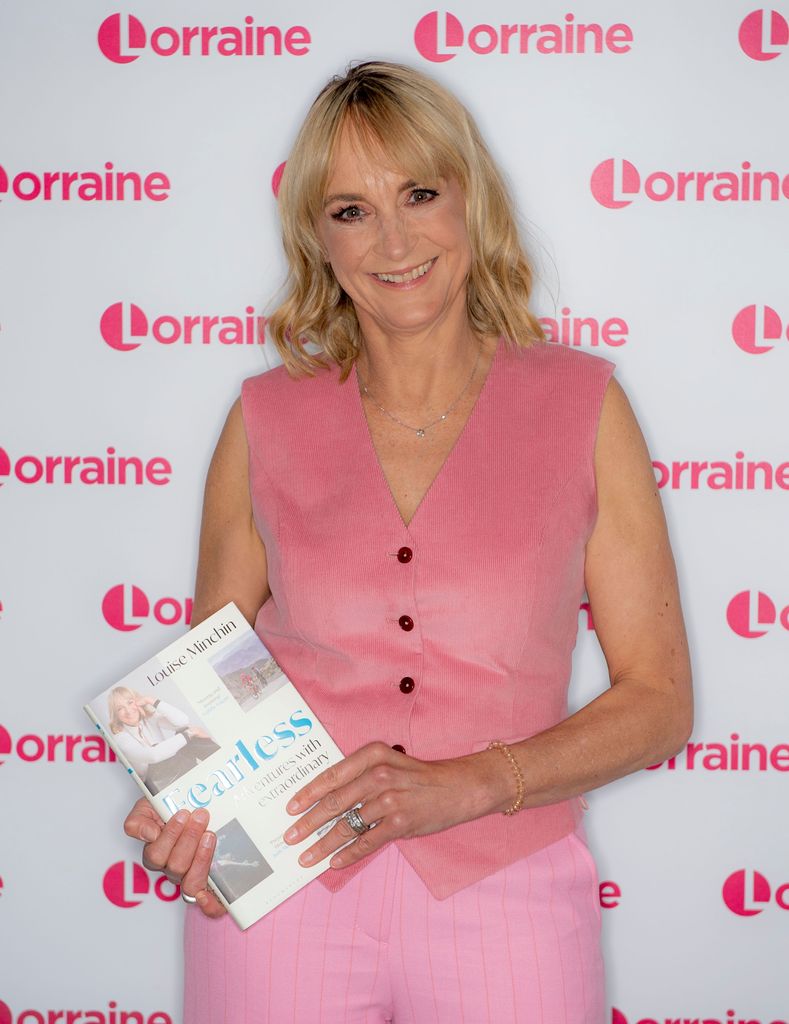 Louise Minchin in pink holding her book