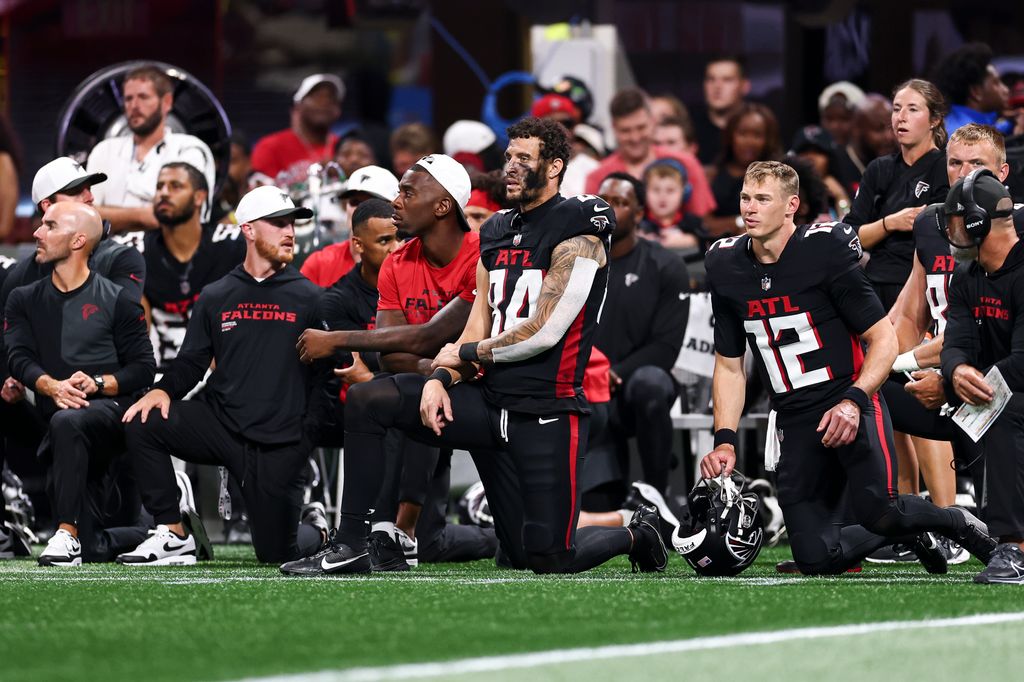 Atlanta Falcons players and coaches kneel together after Morice Norris #26 of the Detroit Lions sustained an injury 