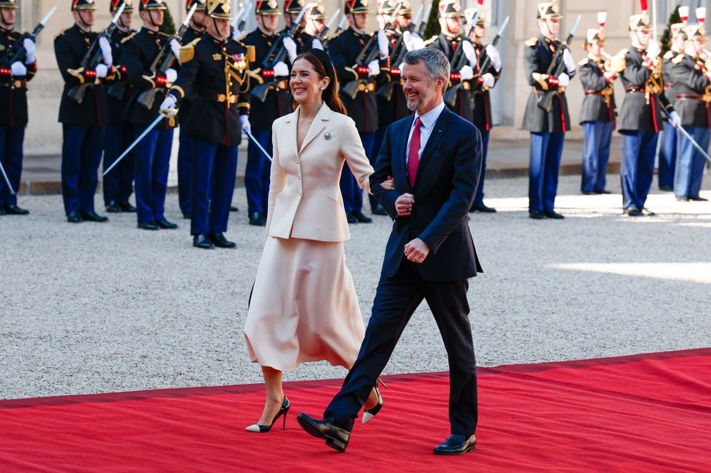 Queen Mary links arms with King Frederik as they arrive at Elysee palace