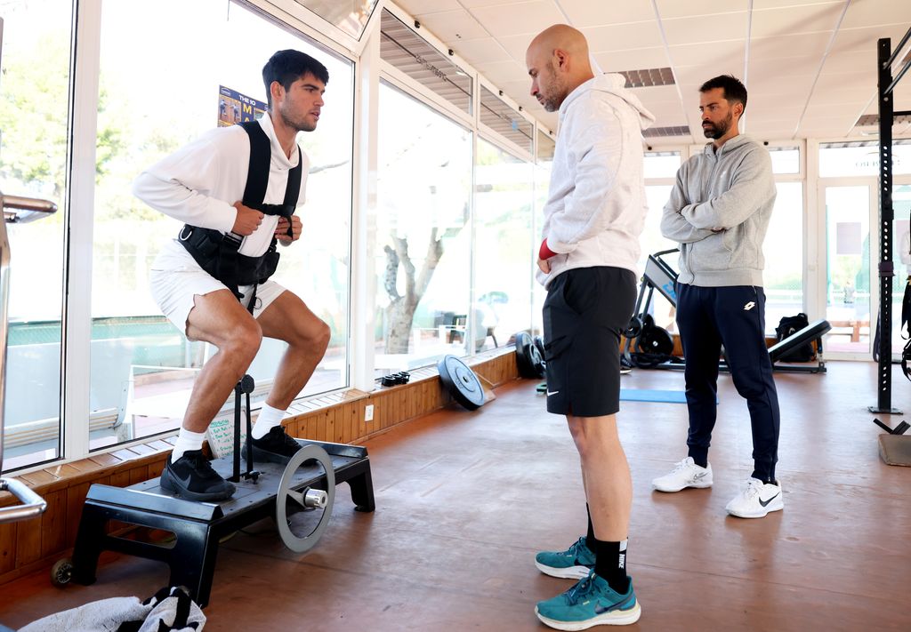 Carlos Alcaraz of Spain watched by his physical trainers Alberto Lledo and Alejandro Sanchez (R) as they are photographed during a pre season gym session in his preparation for next month's Australian Open at Juan Carlos Ferrero Equelite Sports Academy