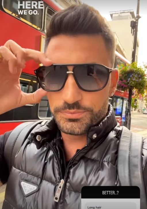 Giovanni Pernice in puffer jacket and sunglasses walking down a street