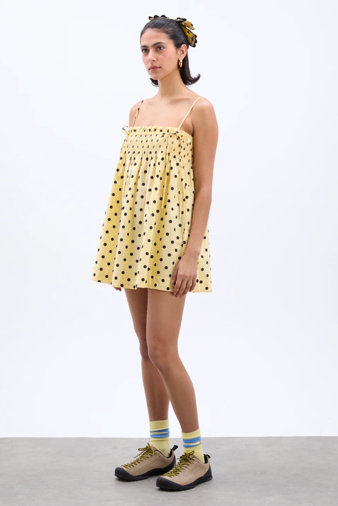 A model poses in a yellow polkadot mini dress for Damson Madder E-commerce