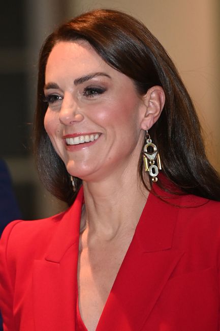 kate smiles in a red suit and shiny earrings