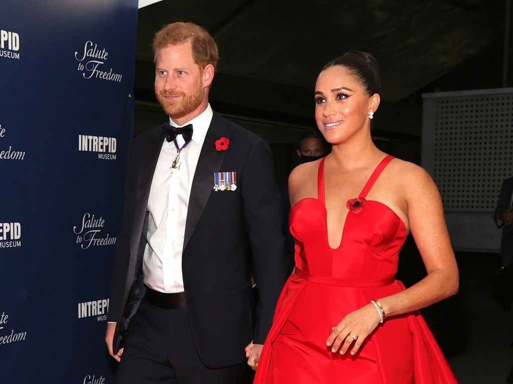 Prince Harry in a suit and Meghan Markle in a red dress