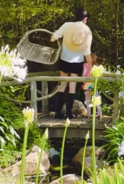 Meghan and Lilibet standing on bridge with basket