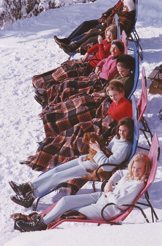 A group of women reclining on the snow in Gstaad with rugs covering their knees, 1963