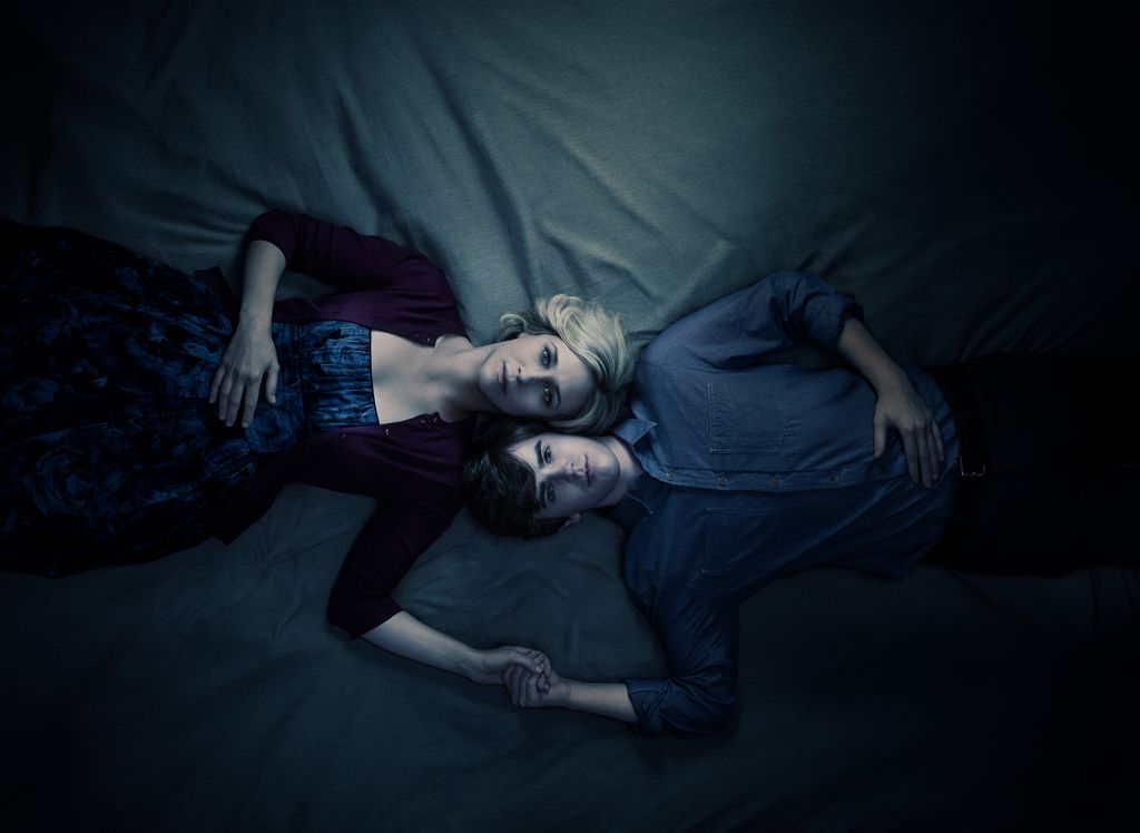 Vera Farmiga as Norma Bates, Freddie Highmore as Norman Bates lying on a matress holding hands